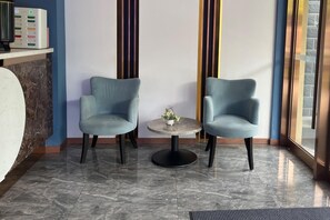 Deux fauteuils placés face à face, avec une petite table ronde entre eux, un vase décoratif sur la table et un sol en marbre.