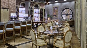 A restaurant interior with brick walls, arched windows, and a large clock on the wall.