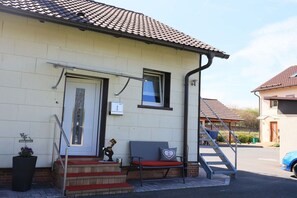 A building with a tiled roof, a front door, a bench, and a staircase leading to the entrance. - Holiday home at Maxschacht (Stockheim)