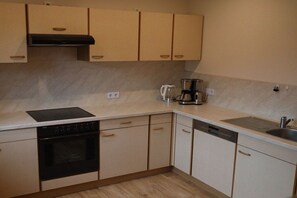 A kitchen with a built-in oven, dishwasher, and a coffee maker on the countertop. - Holiday home at Maxschacht (Stockheim)