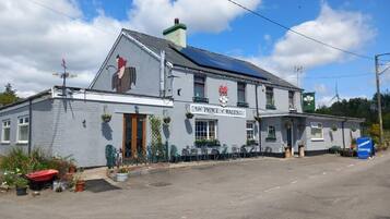 A pub named 'The Prince & Wales' with a traditional architectural style, a signboard, and outdoor seating area.