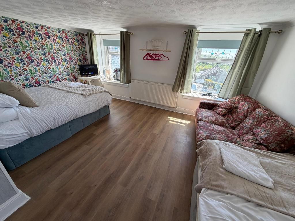 A bedroom with two beds, a radiator, a window with curtains, and a wall with a floral pattern.