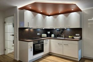Eine moderne Küche mit weißen Schränken, einem schwarzen Backofen und einer Holzarbeitsplatte.