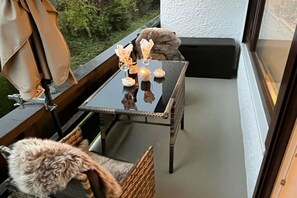 Ein Balkon mit Tisch für zwei Personen, ausgestattet mit einer Kerze und einem dekorativen Gegenstand.