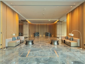 A spacious lobby with a marble floor, two sofas, and two floor lamps. - LN Dongfang Hotel Nansha (Guangzhou)