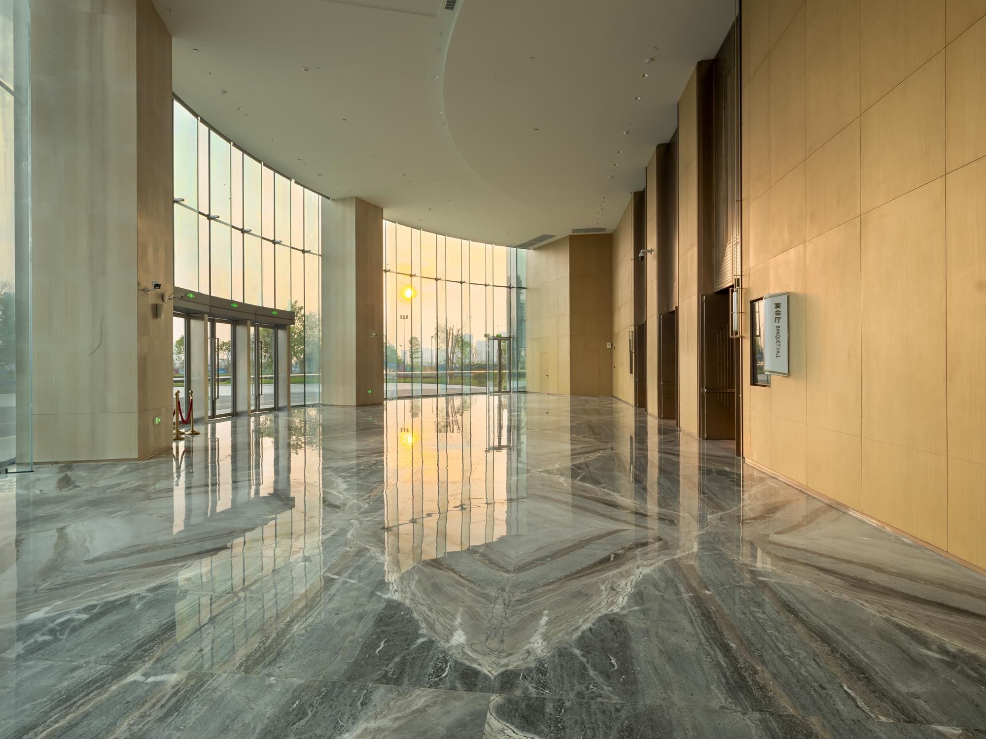 A spacious lobby with a polished marble floor, large windows, and a modern architectural design.