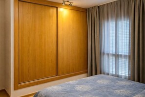 A bedroom with a bed, wooden wardrobe, and a window with curtains. - Apartment in Morro Jable with swimming pool (Morro Jable)