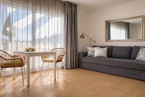 A living room with a grey sofa, two wicker chairs, a white table, and a large mirror on the wall. - Apartment in Morro Jable with swimming pool (Morro Jable)