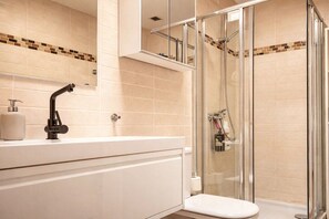 A modern bathroom with a glass-enclosed shower, a white sink, and a mirror above it. - Apartment in Morro Jable with swimming pool (Morro Jable)