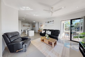 A modern living room with a black leather sofa, a wooden coffee table, and a ceiling fan. - Spacious 3-bed Family Retreat in Darwin (Darwin)
