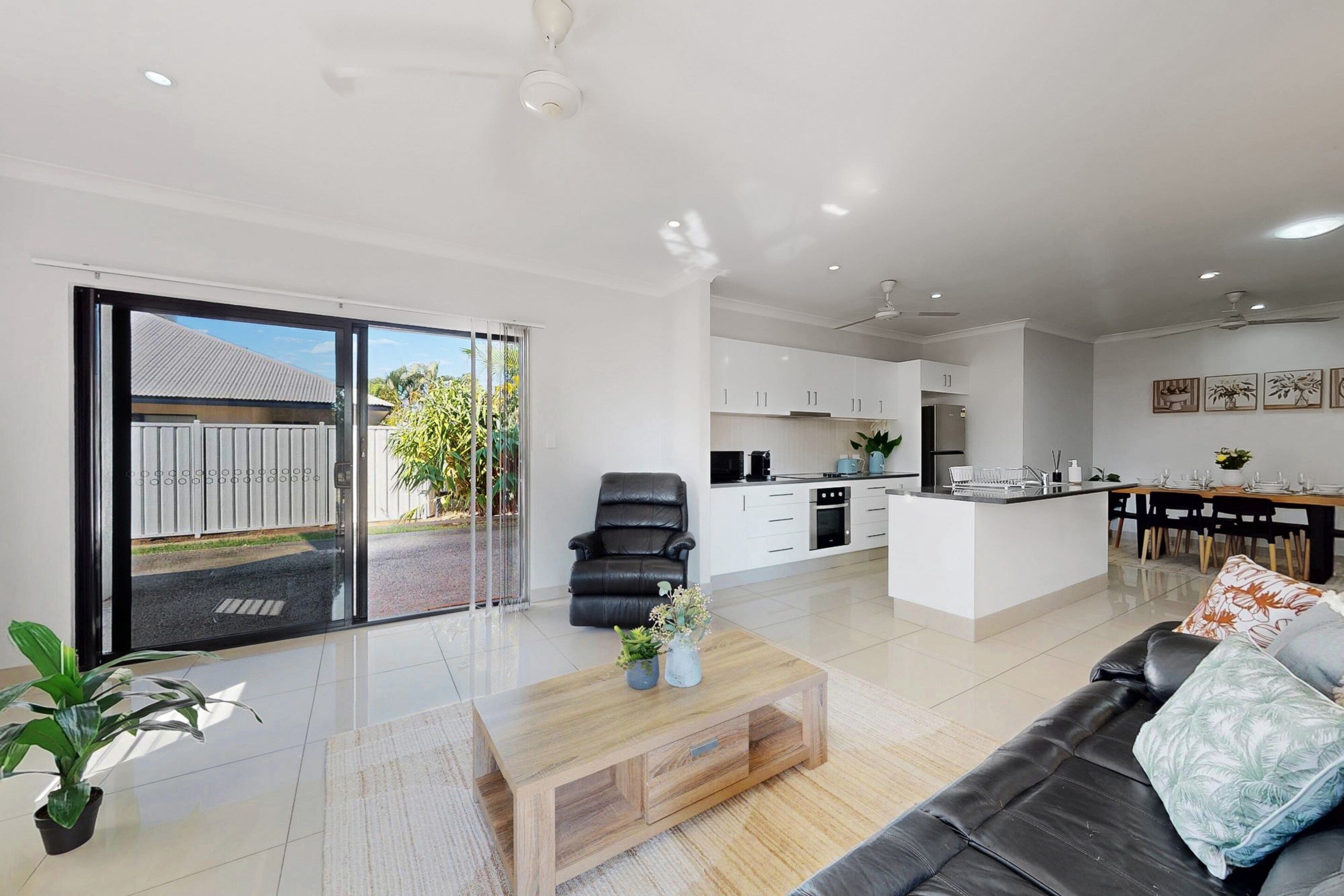 A modern living room with a sofa, a coffee table, and a dining area with a table and chairs.