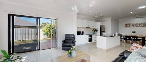 A modern living room with a sofa, a coffee table, and a dining area with a table and chairs.