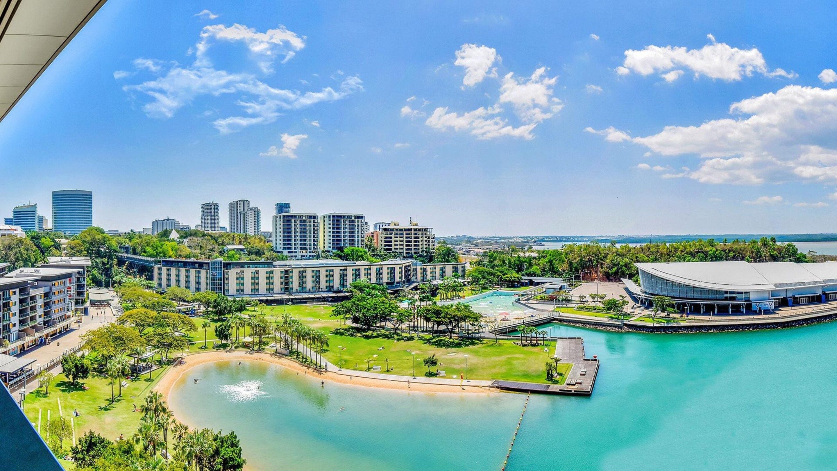 A coastal resort with a swimming pool, a marina, and modern buildings.