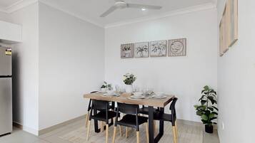 A dining area with a table set for four, black chairs, a ceiling fan, and framed artwork on the wall.