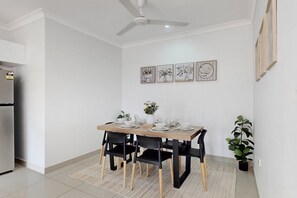 A dining area with a table set for four, black chairs, a ceiling fan, and framed artwork on the wall. - Spacious 3-bed Family Retreat in Darwin (Darwin)