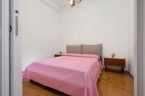 Quarto com cama, mesas de cabeceira, luminária e uma porta.