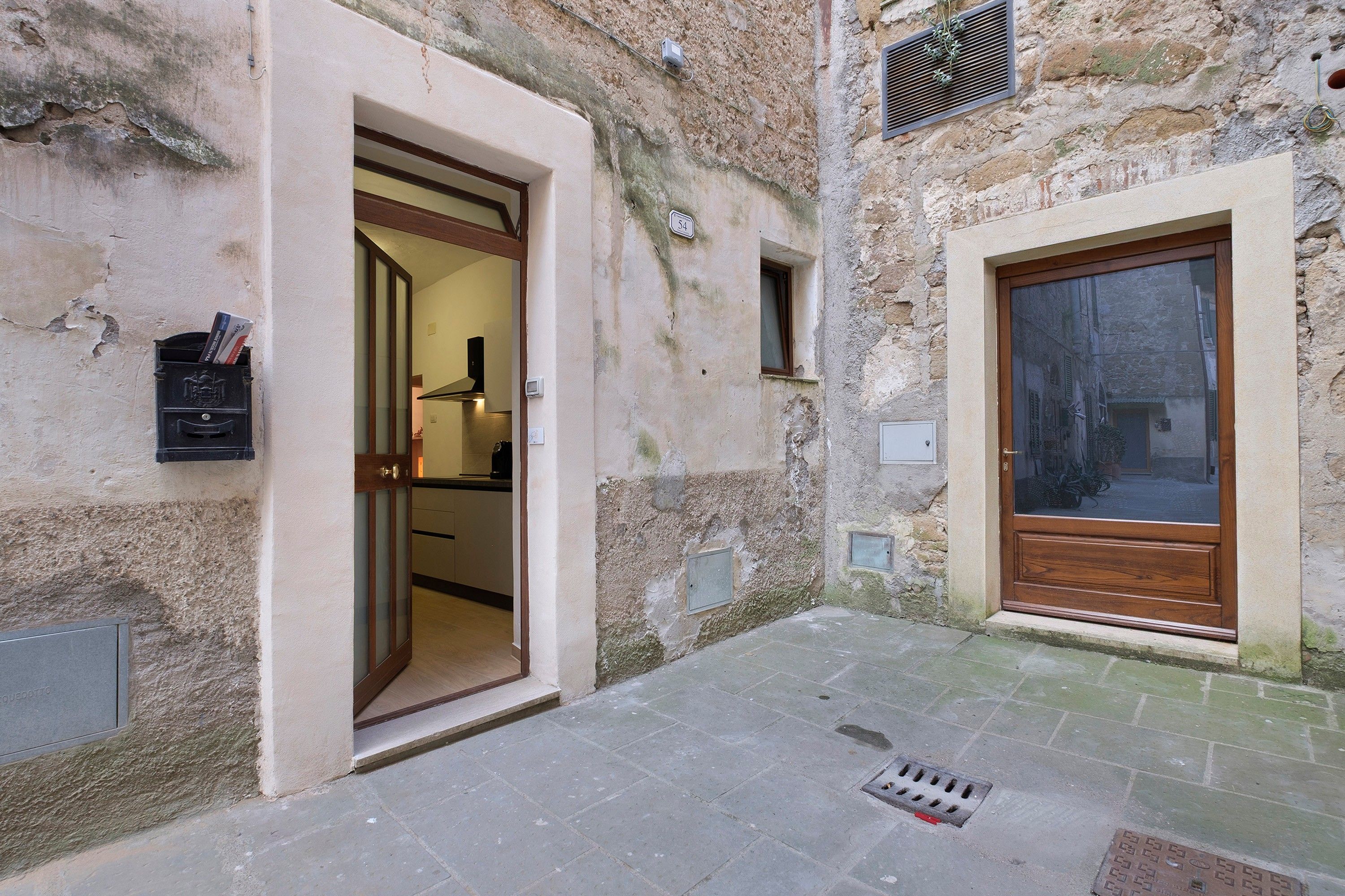 Un callejón estrecho con una puerta de madera y un buzón a la izquierda.