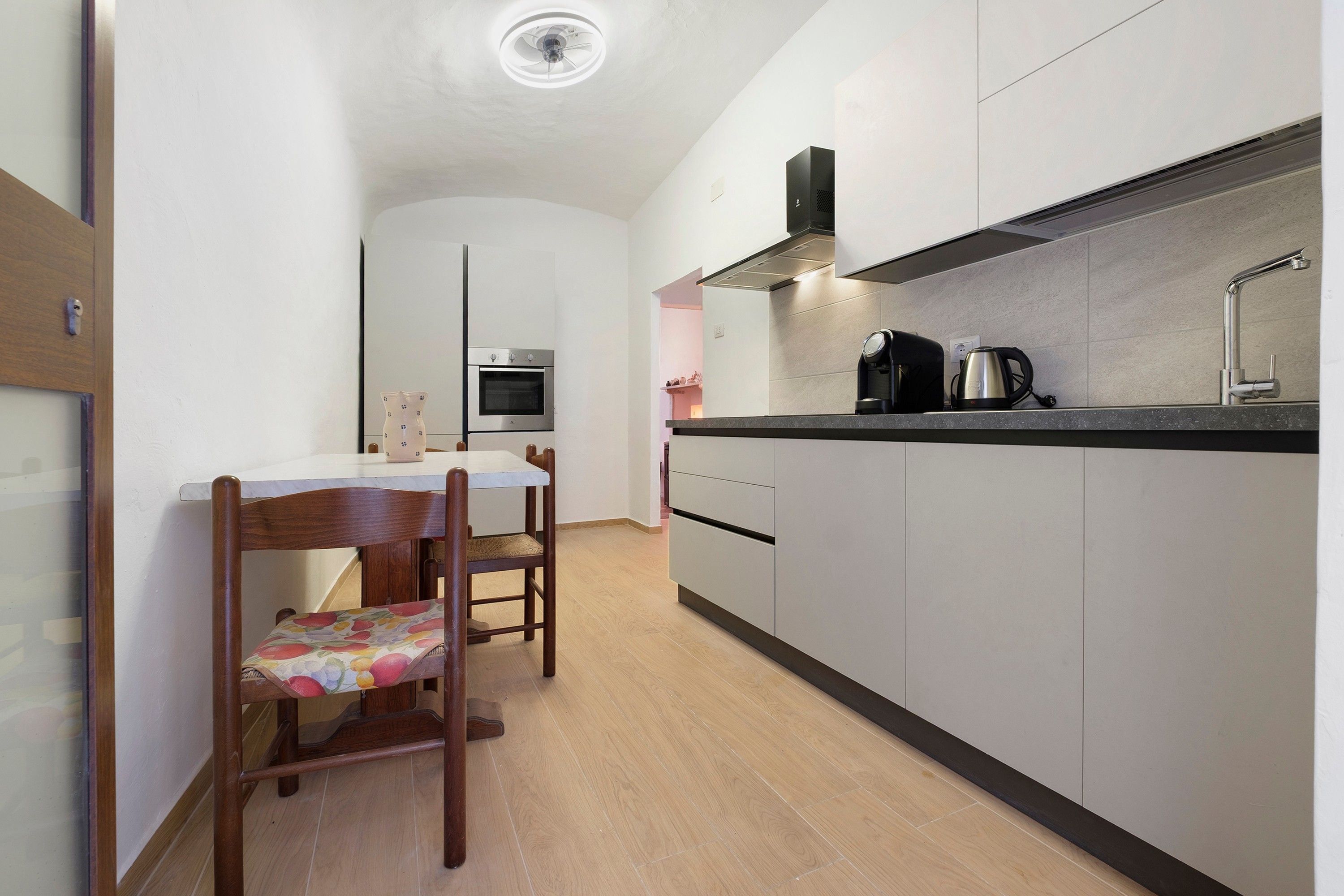 Una cocina compacta con horno integrado, cafetera y hervidor sobre la encimera.