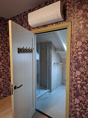 A bathroom with a shower, a towel rack, and a floral-patterned wall. - Vrbo Property (Aarle-Rixtel)