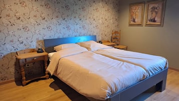 A bedroom with a bed, nightstands, a lamp, and floral wallpaper.