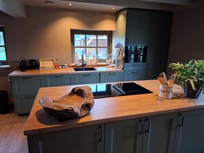 A modern kitchen with a central island, built-in appliances, and a window providing natural light.