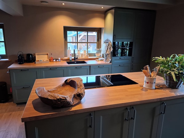 A modern kitchen with a central island, built-in appliances, and a window providing natural light.