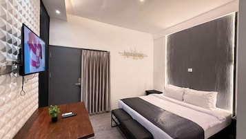 Una habitación de hotel moderna con cama, televisión, escritorio y planta.