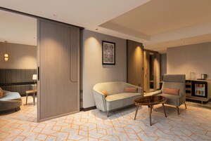 Una habitación de hotel moderna con sofá, sillón y una pequeña mesa redonda.