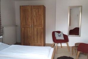 A bedroom with a large wardrobe, a bed, a red chair, a small stool, and a mirror on the wall. - Holiday apartment in Ettal with barbecue (Ettal)