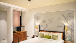 A hotel room with a large bed, a wooden nightstand, a desk, and a wall with a floral mural. - The Sierra-a Luxury Stay (Udaipur)