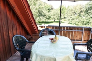 Eine Terrasse im Freien mit einem Tisch, der mit einer weißen Tischdecke bedeckt ist, umgeben von Stühlen und einer Obstschale auf dem Tisch.
