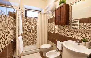 Ein Badezimmer mit Dusche, Toilette, Waschbecken und einem Schrank.