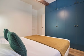 A bedroom with a bed, a green pillow, a brown blanket, and a blue wardrobe. - Apartment in the center of Paris (Paris)