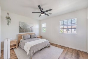 Ein Schlafzimmer mit einem Bett, Nachttischen, einem Deckenventilator und einem Fenster.