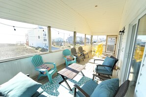 A covered outdoor seating area with chairs and tables, overlooking a residential area. - Amazing  Beach House with steps to the beach, Ocean views! (North Topsail Beach)
