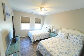 A bedroom with two beds, a ceiling fan, a TV, and a window with blinds. - Amazing  Beach House with steps to the beach, Ocean views! (North Topsail Beach)