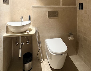 A bathroom with a white sink, toilet, and shower. - Hotel Dakshin Grand  (Navi Mumbai)