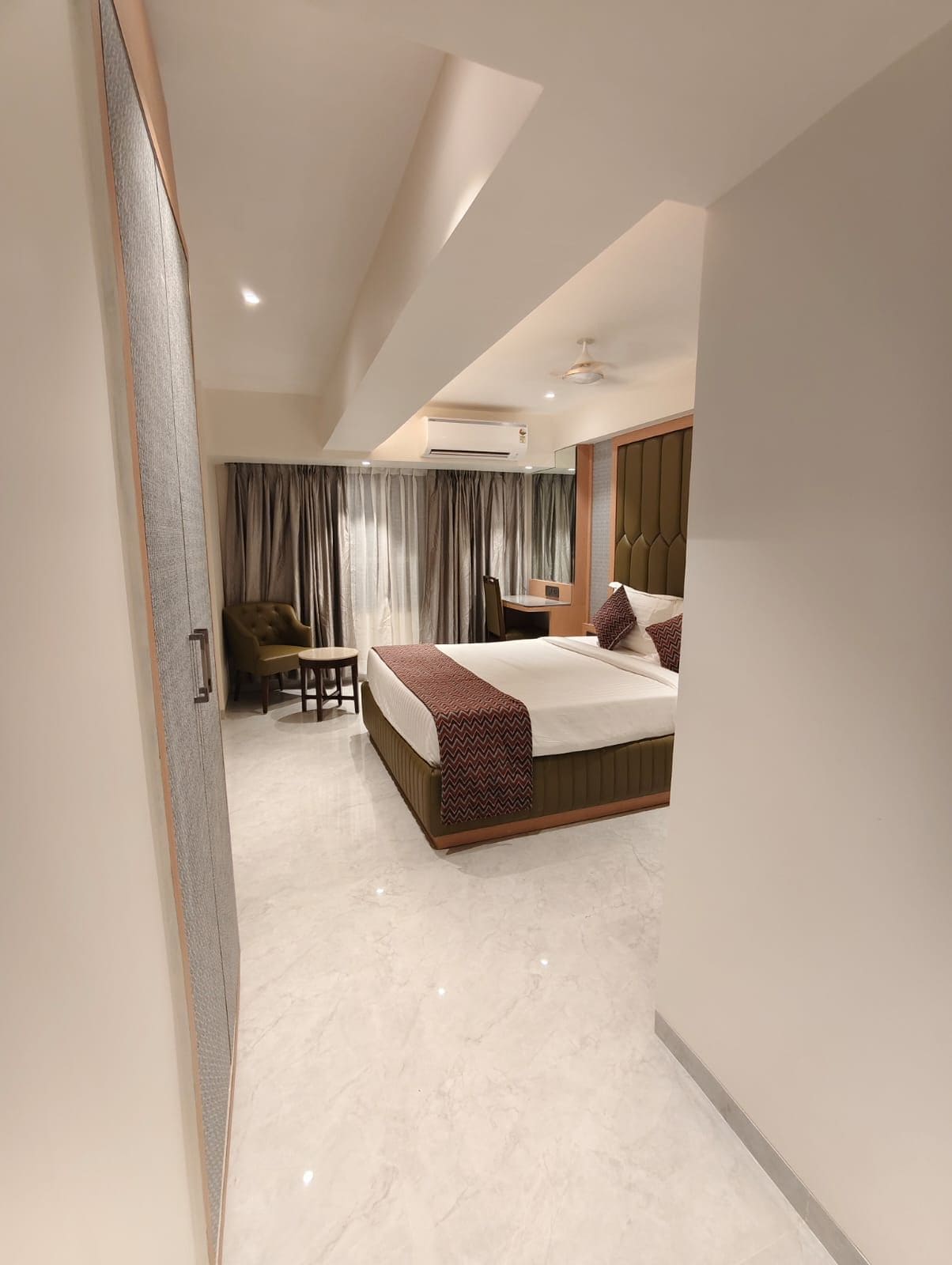 A modern hotel room with a large bed, a desk, and a chair.