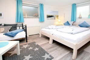 A bedroom with two beds, a window with curtains, a radiator, and a star-patterned rug. - Starklef 1, Holiday Apartment 3, Rungholt (Wyk auf Föhr)