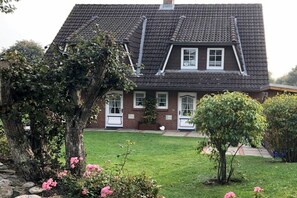 A two-story house with a sloped roof, a front porch, and a well-maintained lawn. - Starklef 1, Holiday Apartment 3, Rungholt (Wyk auf Föhr)