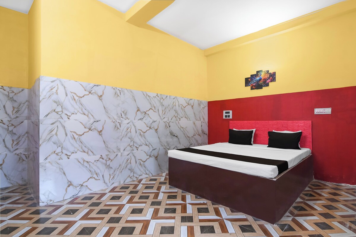 Una habitación con una cama, cabecera roja, pared con diseño de mármol y suelo con estampado geométrico.