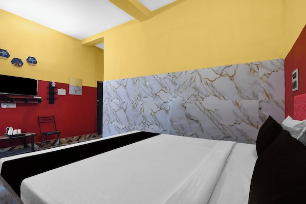 Quarto de hotel com cama, escrivaninha e cadeira.