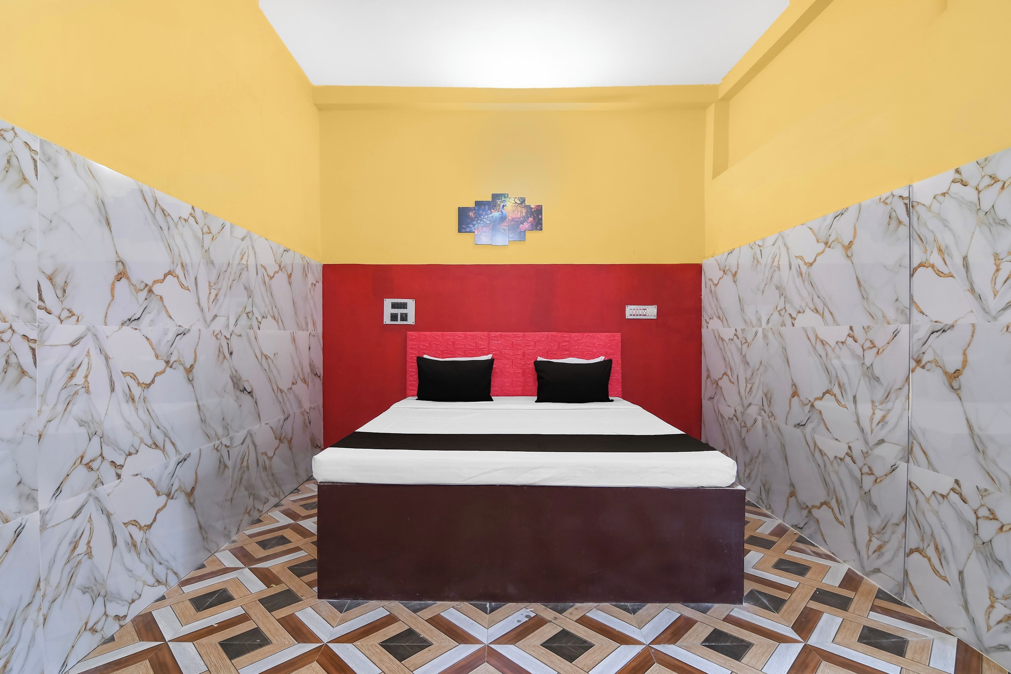 A room with a bed, a red accent wall, and marble-patterned walls.