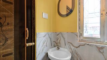 A bathroom with a marble wall, a white sink, and a mirror.