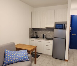 A compact kitchen with a refrigerator, microwave, sink, and cabinets. - Renovated studio apartment just steps from the sea (Bibione)