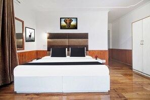 A bedroom with a large bed, a headboard with horizontal panels, a framed picture of an elephant, and a mirror on the wall. - Hotel O Zero Bridge Formerly Time Star (Srinagar)