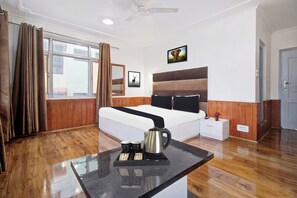 A hotel room with a bed, a bedside table with a kettle, a nightstand, a window with curtains, and a wall with framed pictures. - Hotel O Zero Bridge Formerly Time Star (Srinagar)