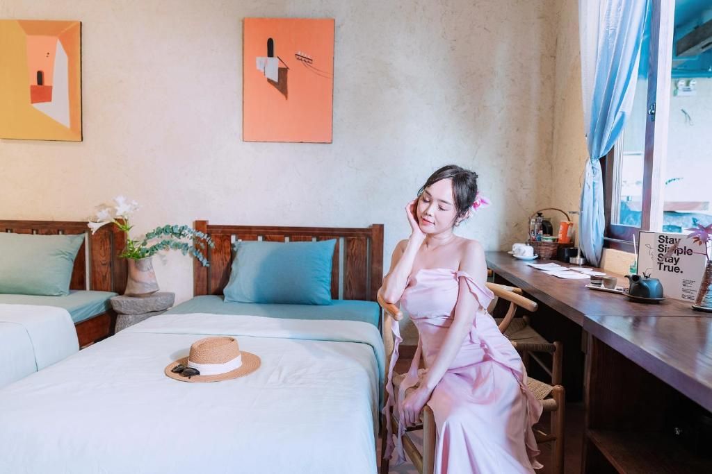 A hotel room with a bed, a chair, a desk, and a window with curtains.