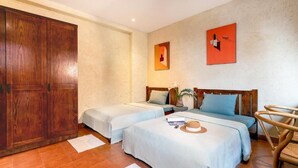 Habitación de hotel con dos camas, un armario de madera y una sola silla.