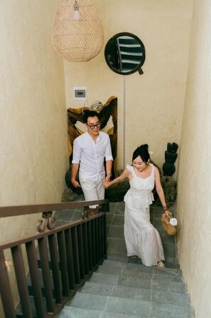 A staircase with a metal railing, a wall-mounted light fixture, and a decorative wall hanging. - Ve Homestay Ninh Bình (Nam Hoa Lư)